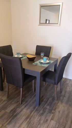 A dining table with four chairs and a mirror above it.