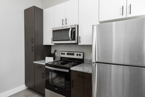 A modern kitchen with a stainless steel refrigerator, microwave, and oven.