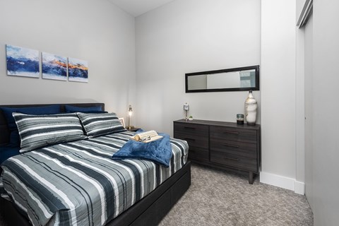 A bedroom with a bed, nightstand, and a painting on the wall.