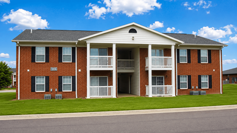 A two-story brick apartment building with a balcony on the second floor.