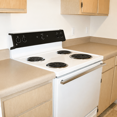 A white stove with four burners sits in a kitchen.