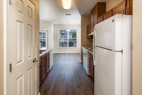 A kitchen with a white refrigerator and wooden floors.