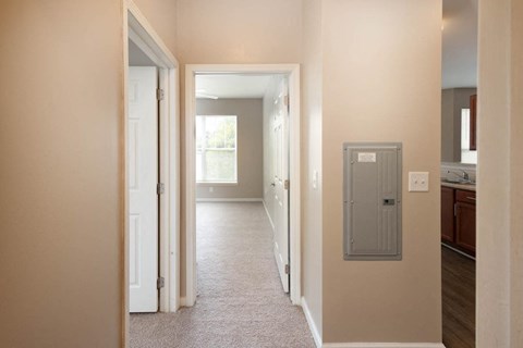 A hallway with a door on the left and a utility box on the wall on the right.