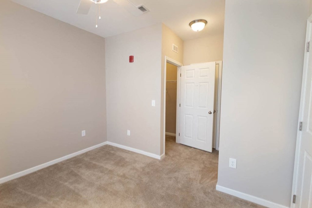 a room with a carpeted floor and a door to a closet