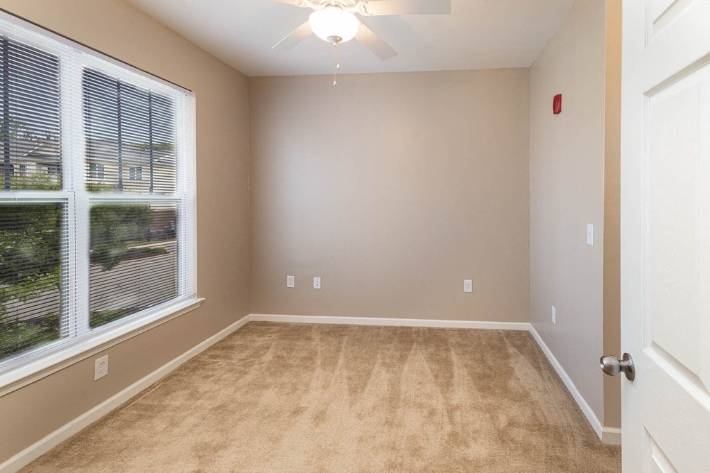 an empty living room with a large window and carpet