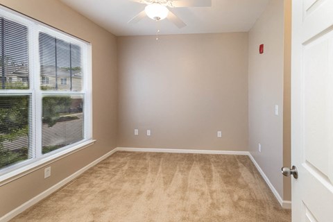 an empty living room with a large window and carpet
