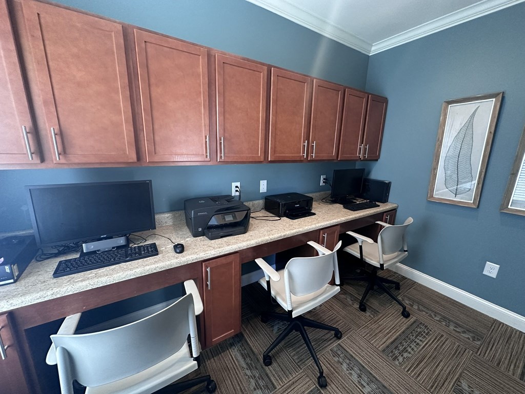 an office with two computers and a desk with chairs