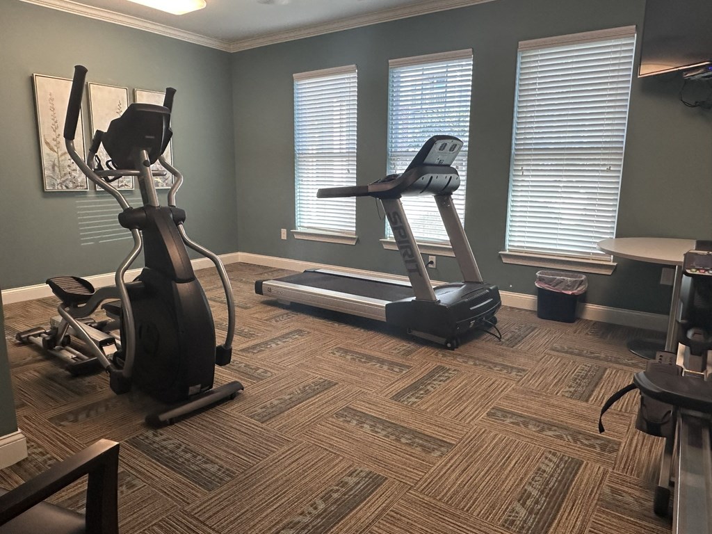 a home gym with exercise equipment and three windows