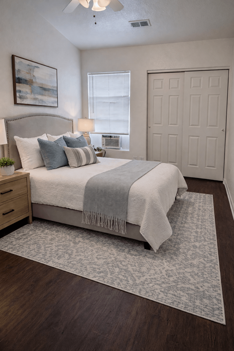 A bedroom with a bed, a ceiling fan, and a rug.