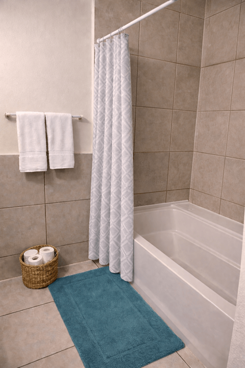 A white shower curtain hangs over a white bathtub in a bathroom.