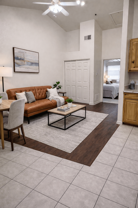 A living room with a brown couch and a white ceiling fan.