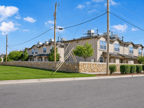 A row of houses with a stone wall in front.
