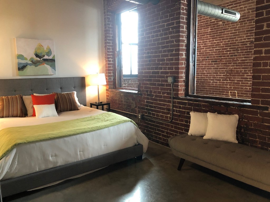 a bedroom with a bed and a couch and a window