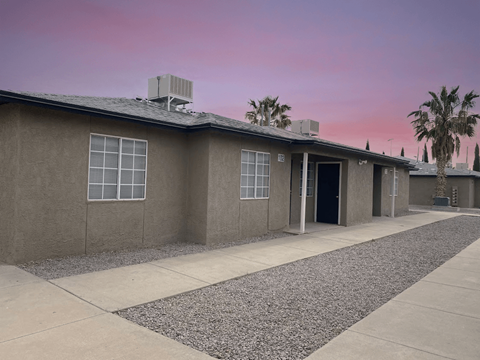 A building with a grey roof and a palm tree in front.