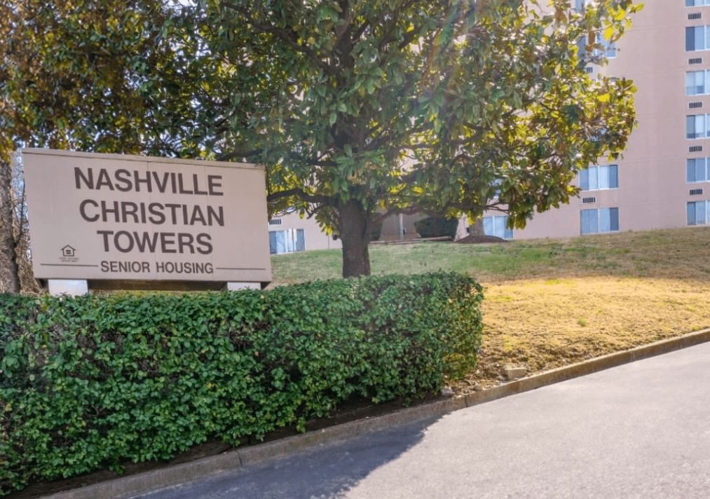 a sign towers in front of a tree