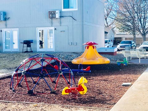 a playground in a yard with a swing set and other toys