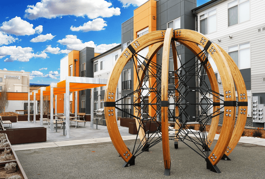 a group of wooden playground equipment in front of buildings