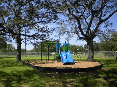A playground with a blue slide and green swing set.