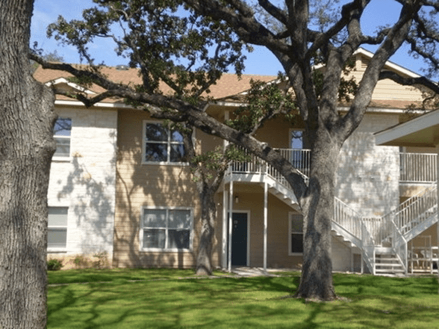 an apartment building with stairs and trees in front of it