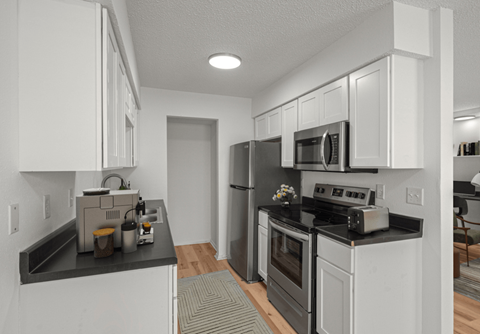 A modern kitchen with white cabinets and black countertops.
