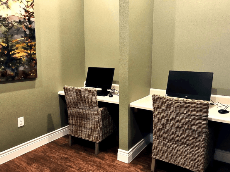 a home office with two chairs and a desk with two computers