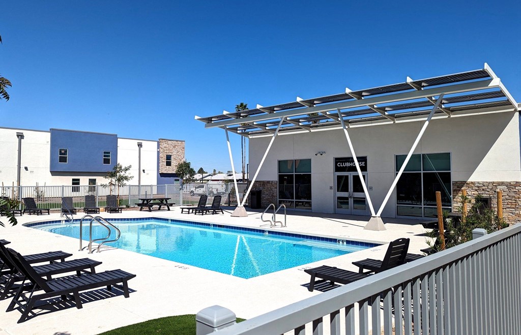 A pool with sun loungers and a building with a sign that says "Clubhouse".