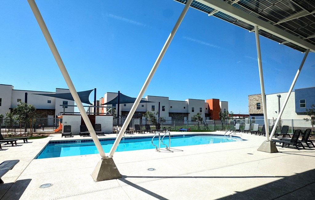 A pool surrounded by a white fence and a white building in the background.