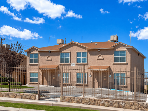 A large house with a brown roof and a pool in the front yard.
