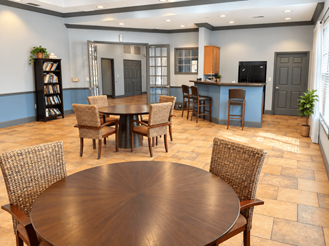 A dining room with a large table surrounded by chairs.