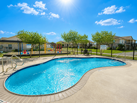 A sunny day at a pool with a slide and a playground.