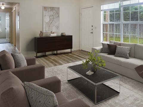 A living room with a brown sofa, a grey armchair, a black coffee table, and a white door.