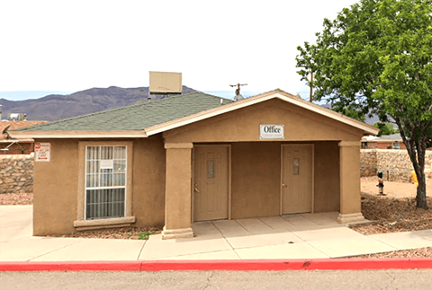 A small brown building with a green roof and a sign that says Office.