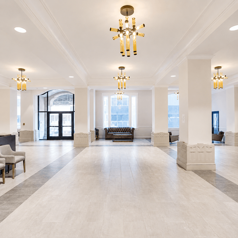 A large, well-lit lobby with a chandelier and a bench.
