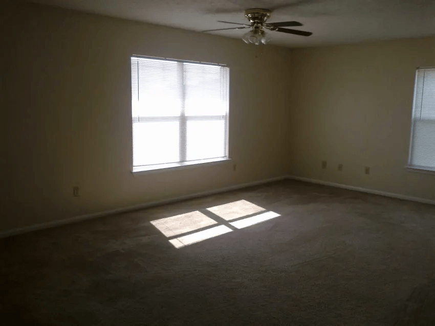 an empty room with a window and a ceiling fan