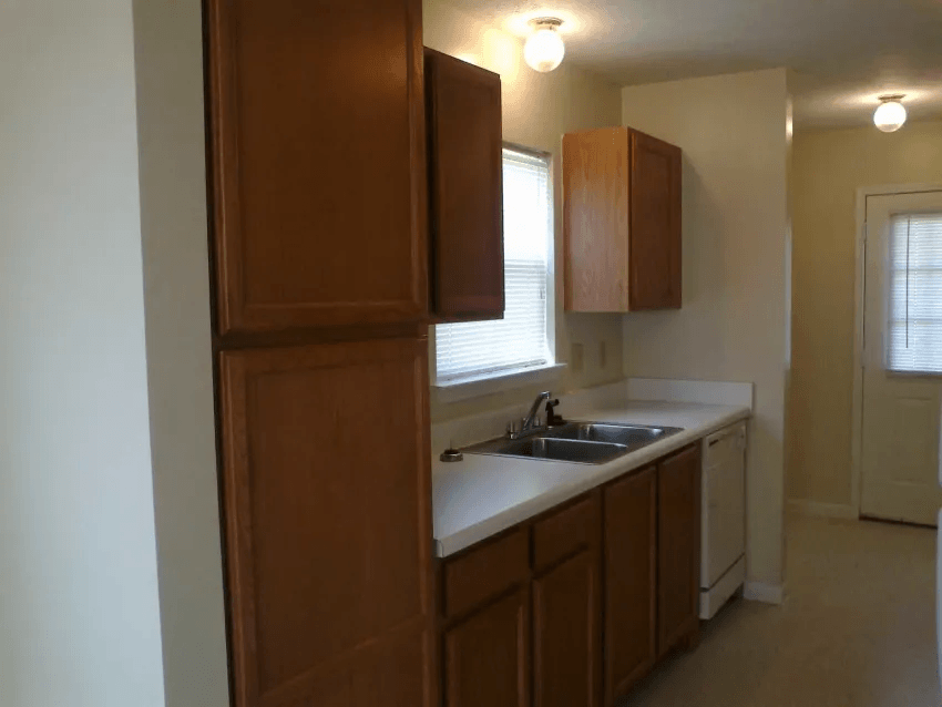 an empty kitchen with a sink and wooden cabinets