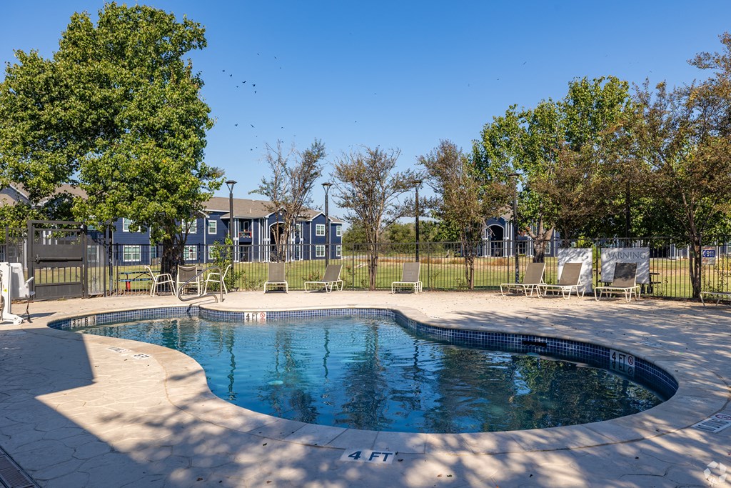 A small pool surrounded by trees and chairs.
