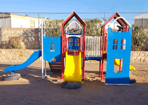 A playground with a blue slide and a yellow slide.