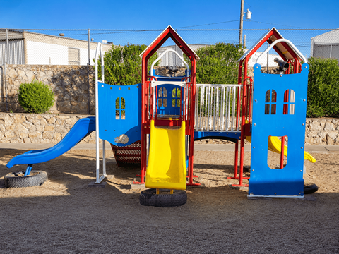 A playground with a blue slide and two red and blue houses.