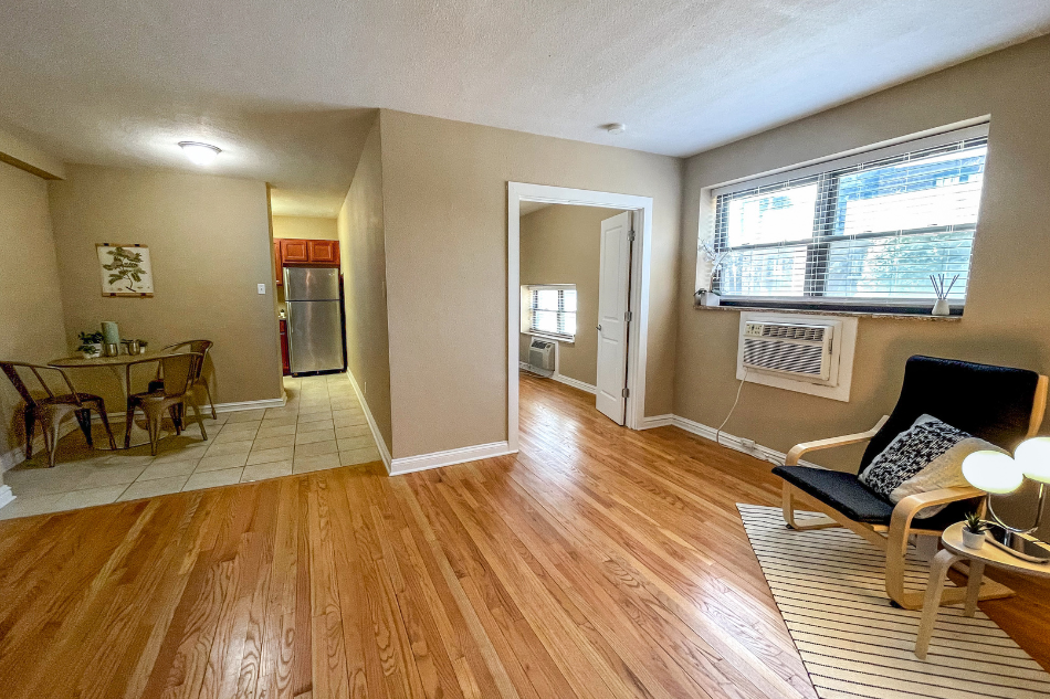 an open living room and dining room with hard wood floors and a window
