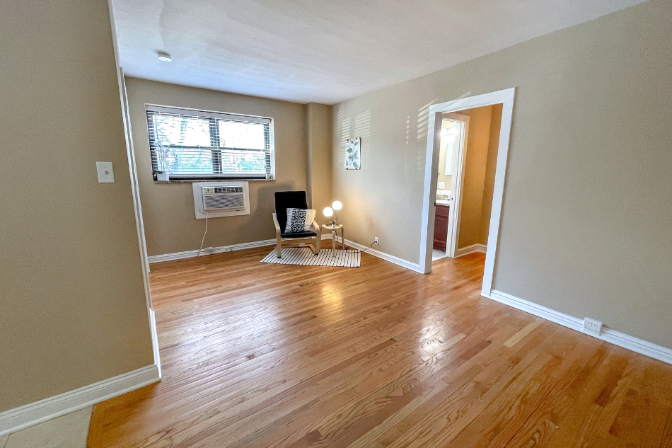 an empty living room with hard wood floors and a window