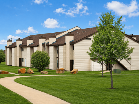 A tree stands in front of a building with a walkway in front of it.