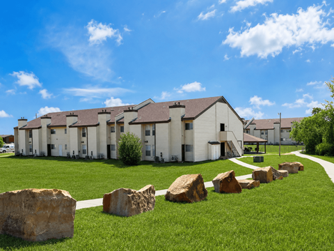 A row of houses with a grassy front yard and large rocks in the foreground.
