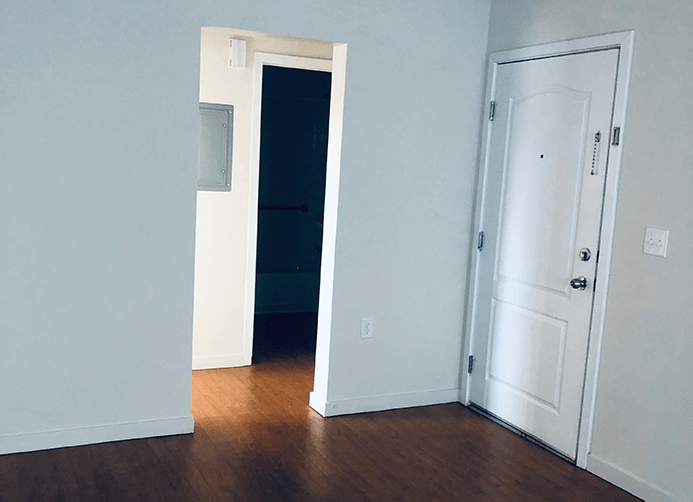 an empty room with a door to a hallway and a closet