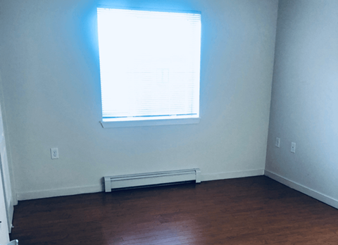 an empty room with a window and wooden floors