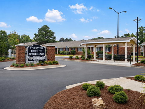 A sign for Riverview Heights Apartments stands in front of a building.
