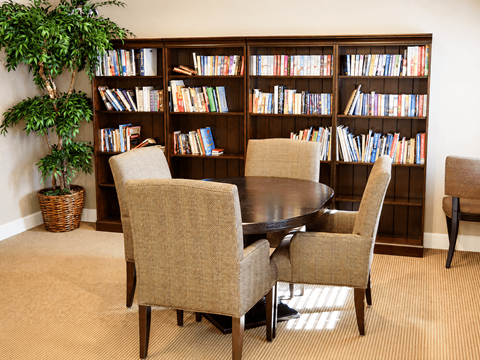A room with a large bookshelf filled with books and a table with chairs.