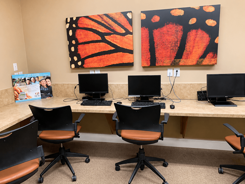 A room with a desk and chairs and two paintings on the wall.