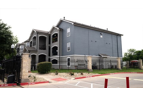 an apartment building with a blue exterior and a fence
