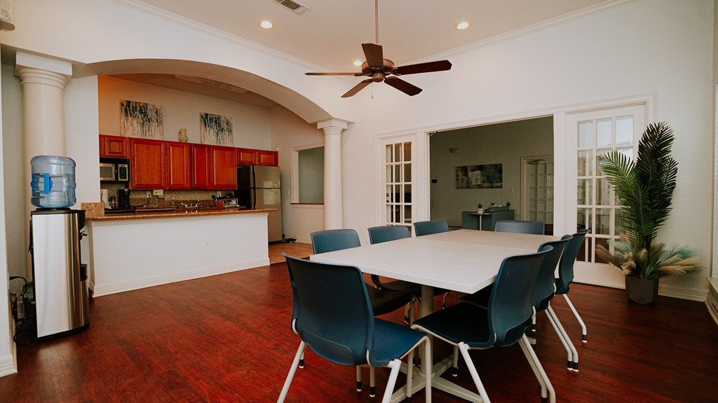 a dining room with a white table and chairs and a kitchen
