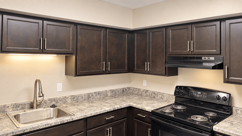 A kitchen with dark brown cabinets and a black stove top oven.